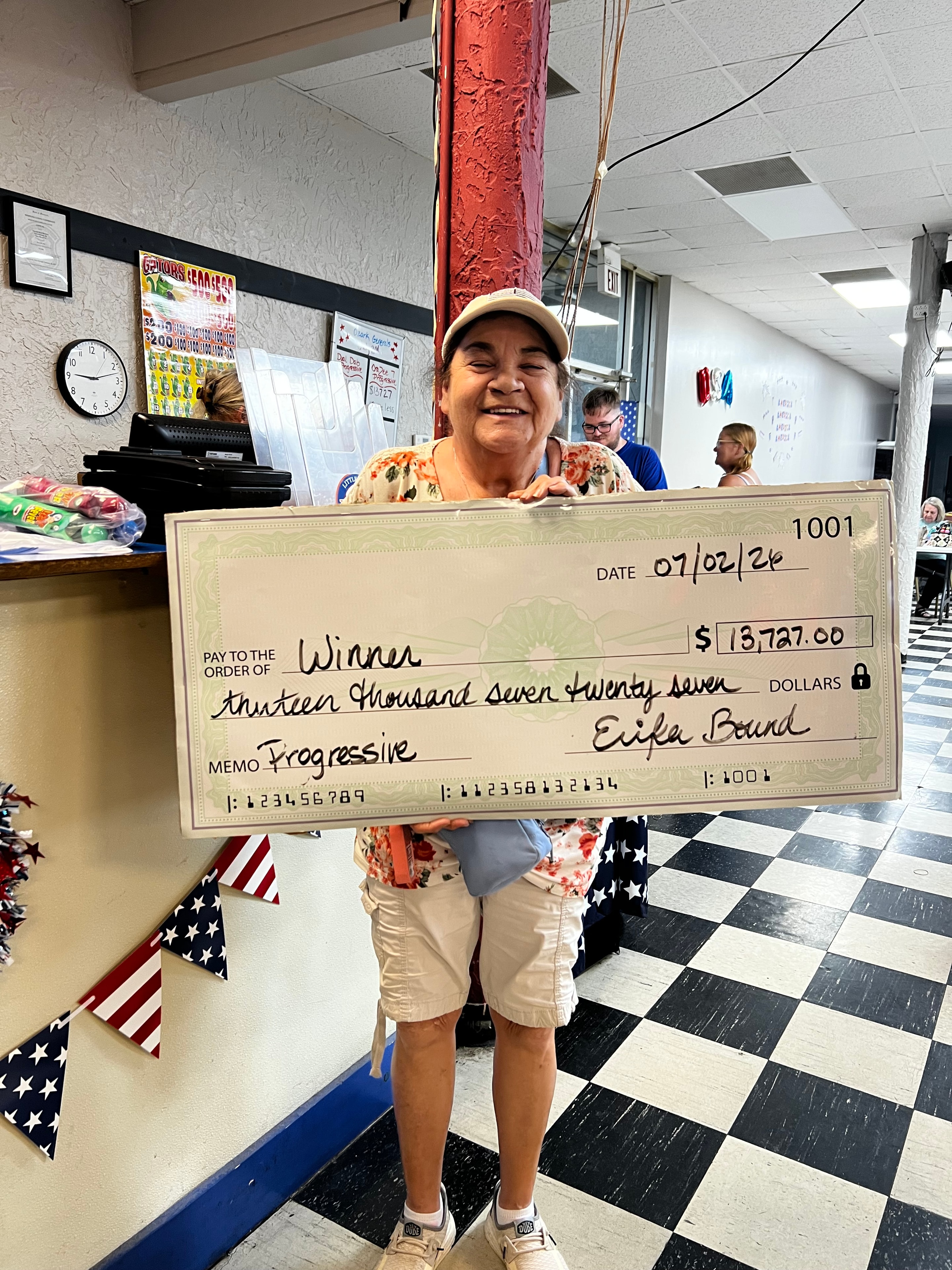 Winner holding $13,727 progressive jackpot check